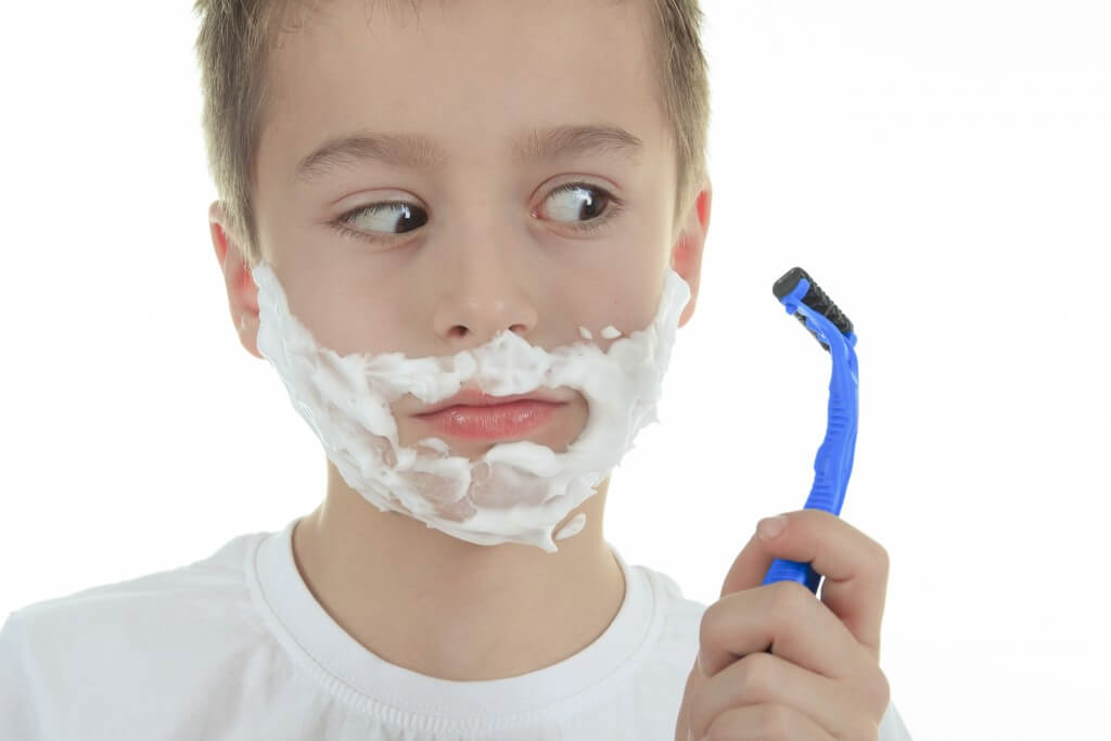playful little young boy shaving face over white background