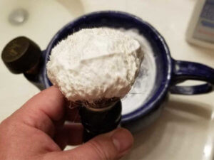 the art of shaving sandalwood shaving cream loaded onto a shave brush