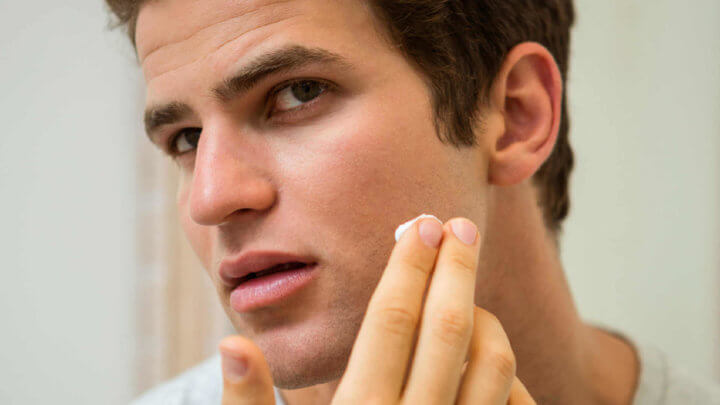 man applying lotion to face