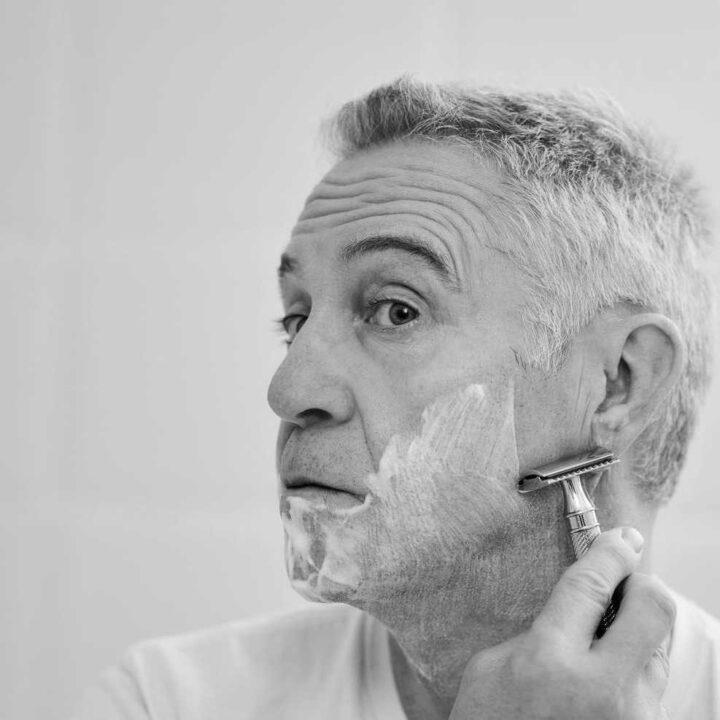 man shaving face with double edge razor