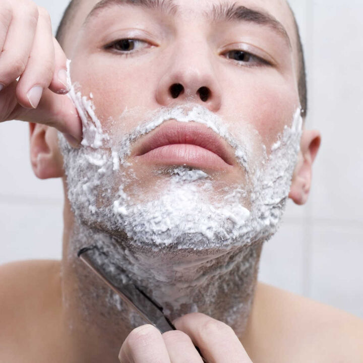 man shaving with straight razor