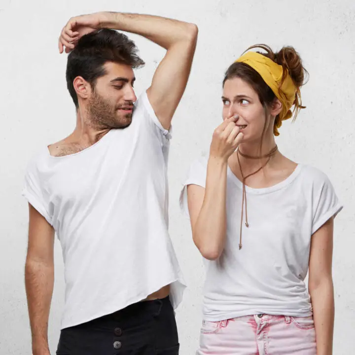 man showing armpit to woman