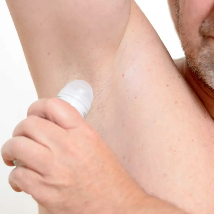 man applying deodorant to armpit