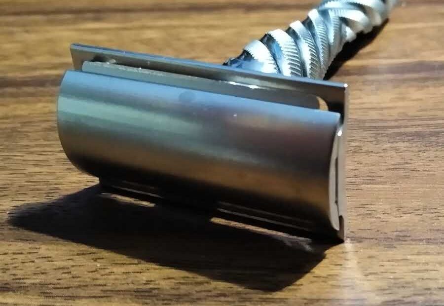 closeup of double edge razor resting on wood shelf