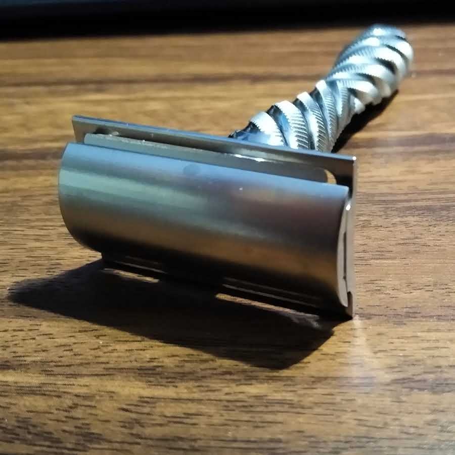 closeup of double edge razor resting on wood shelf