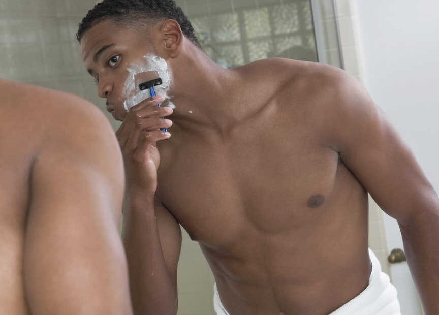 man shaving in front of mirror