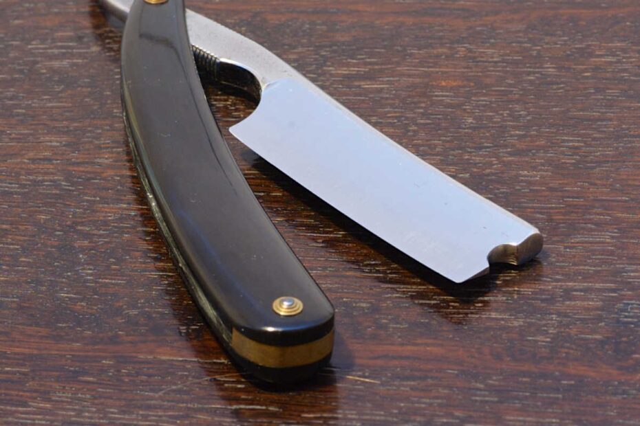 straight razor partly open, resting on wood shelf
