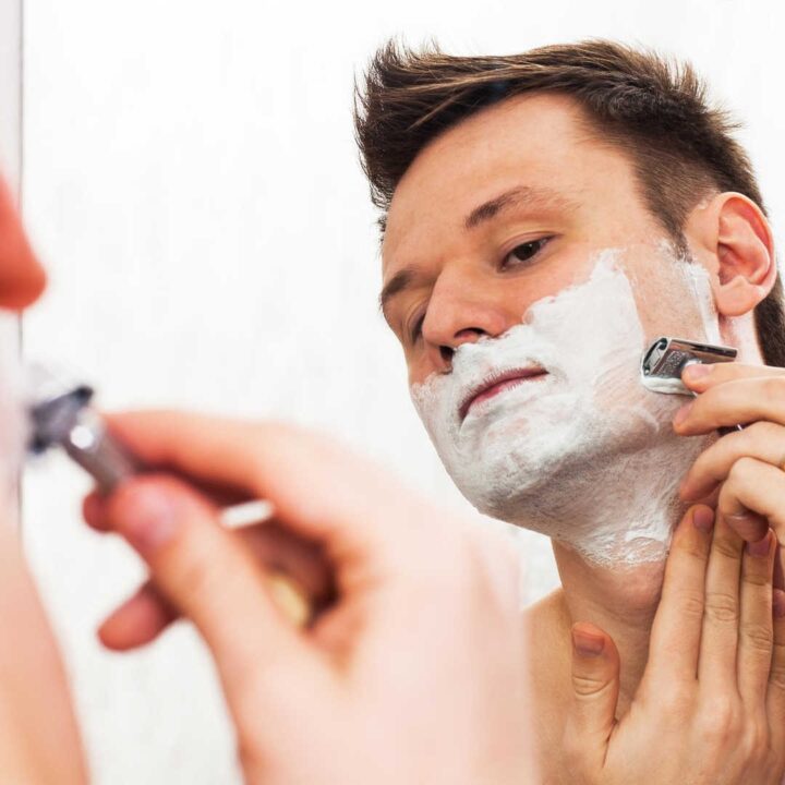 man shaving with safety razor introspectively