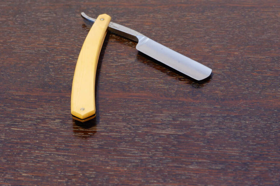 open straight razor on simple wood table