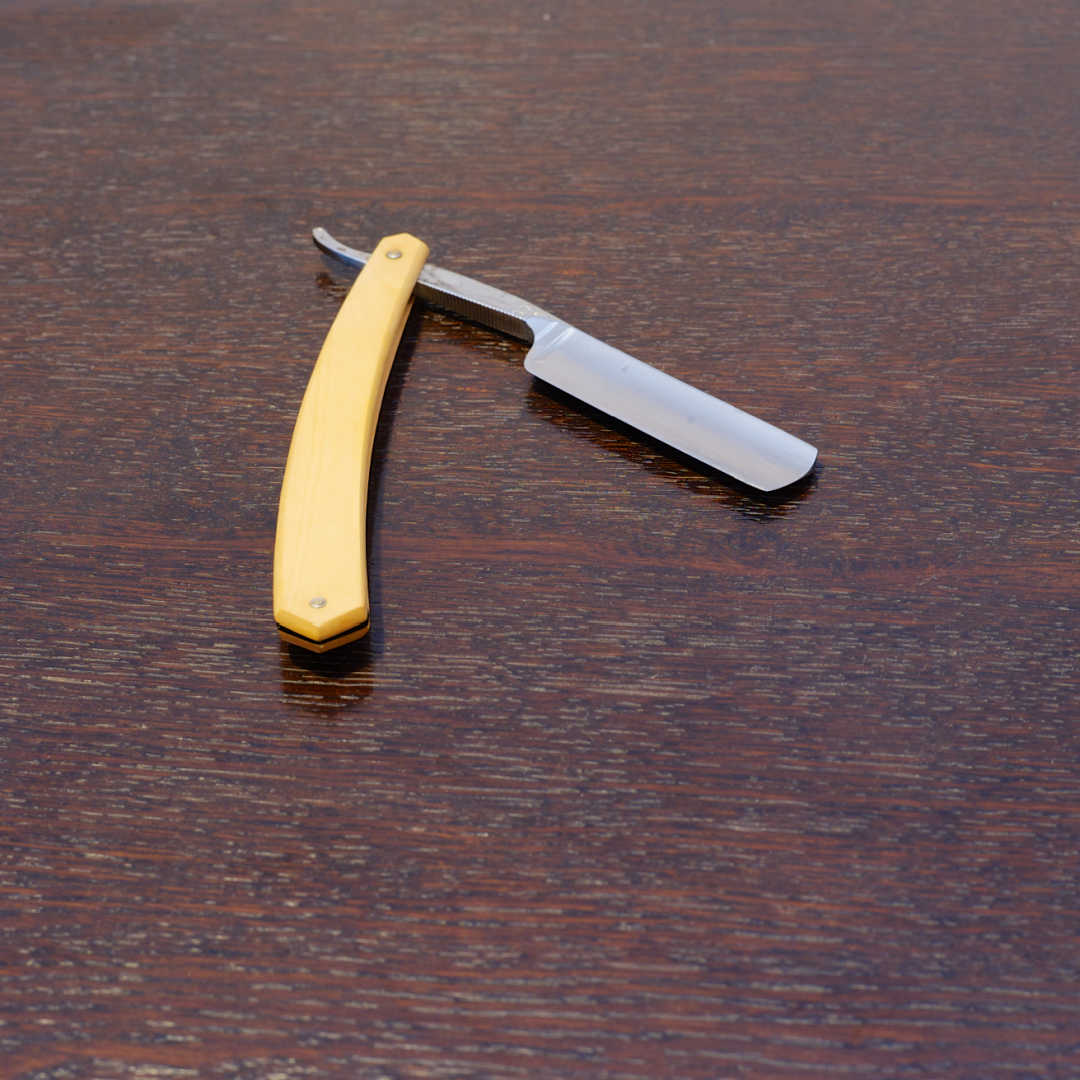 open straight razor on simple wood table